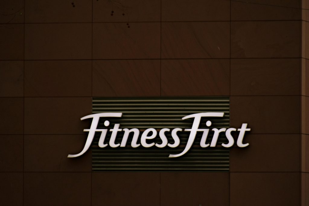 Close-up of FitnessFirst gym sign on a contemporary brown wall.