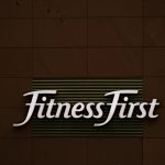 Close-up of FitnessFirst gym sign on a contemporary brown wall.