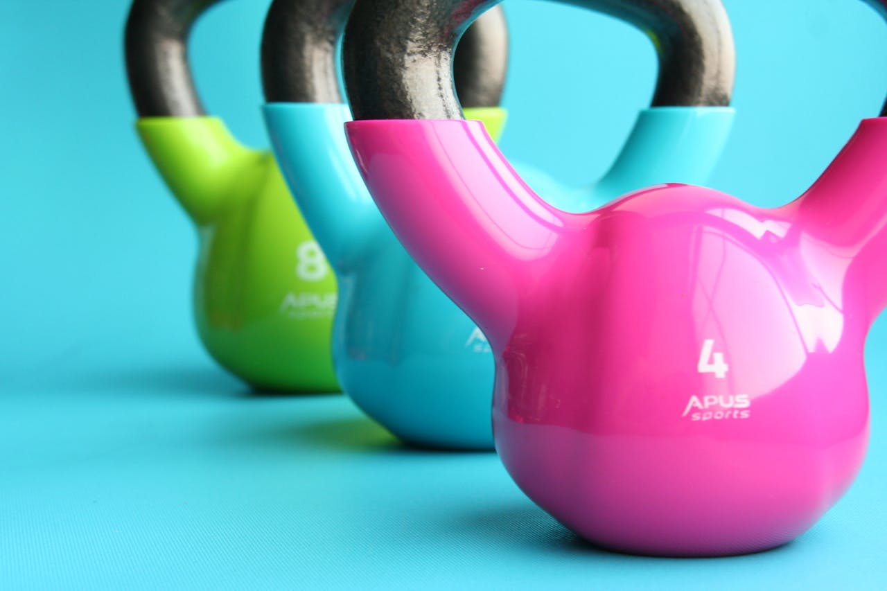 about-03 Vibrant colored kettlebells on blue background highlighting fitness and exercise equipment.