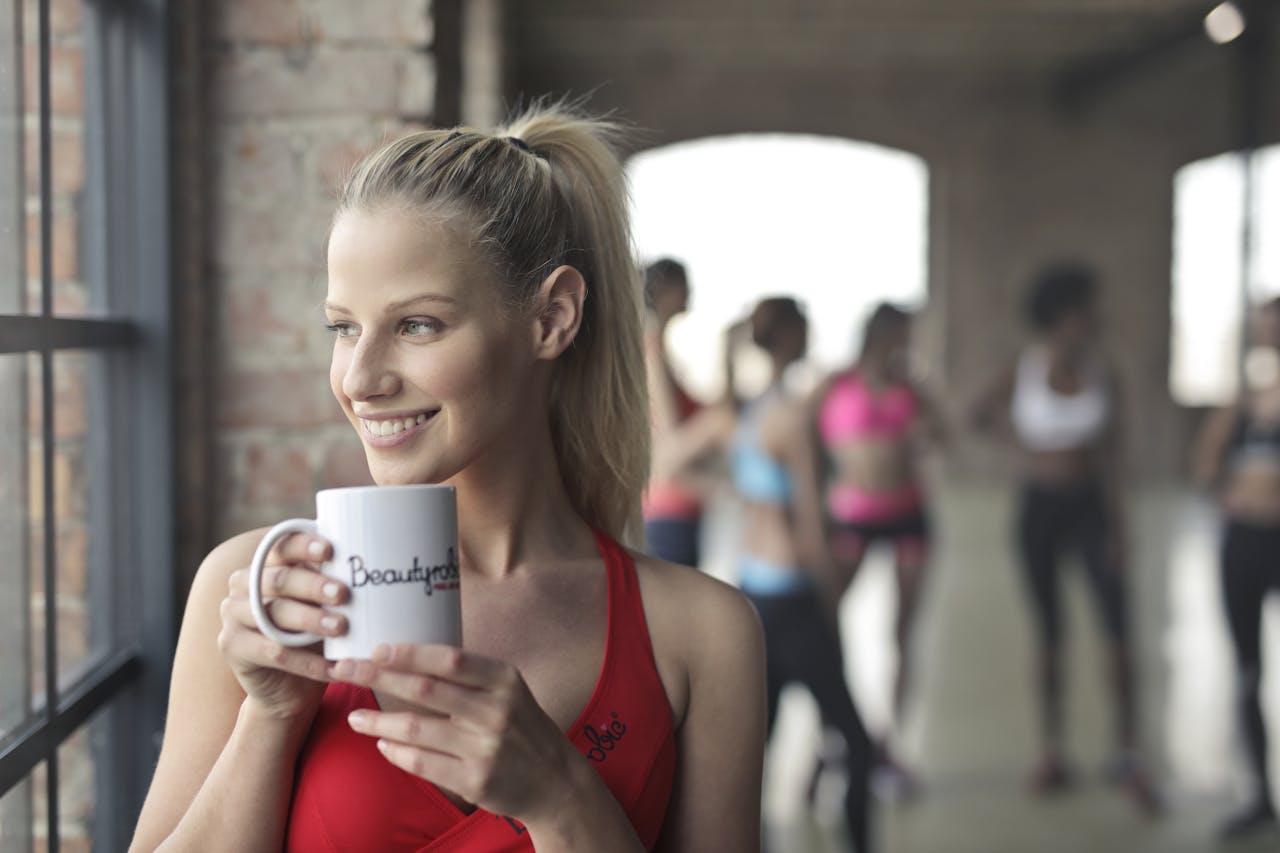 services-06 Woman in activewear enjoying a coffee break indoors at a gym in Budapest.